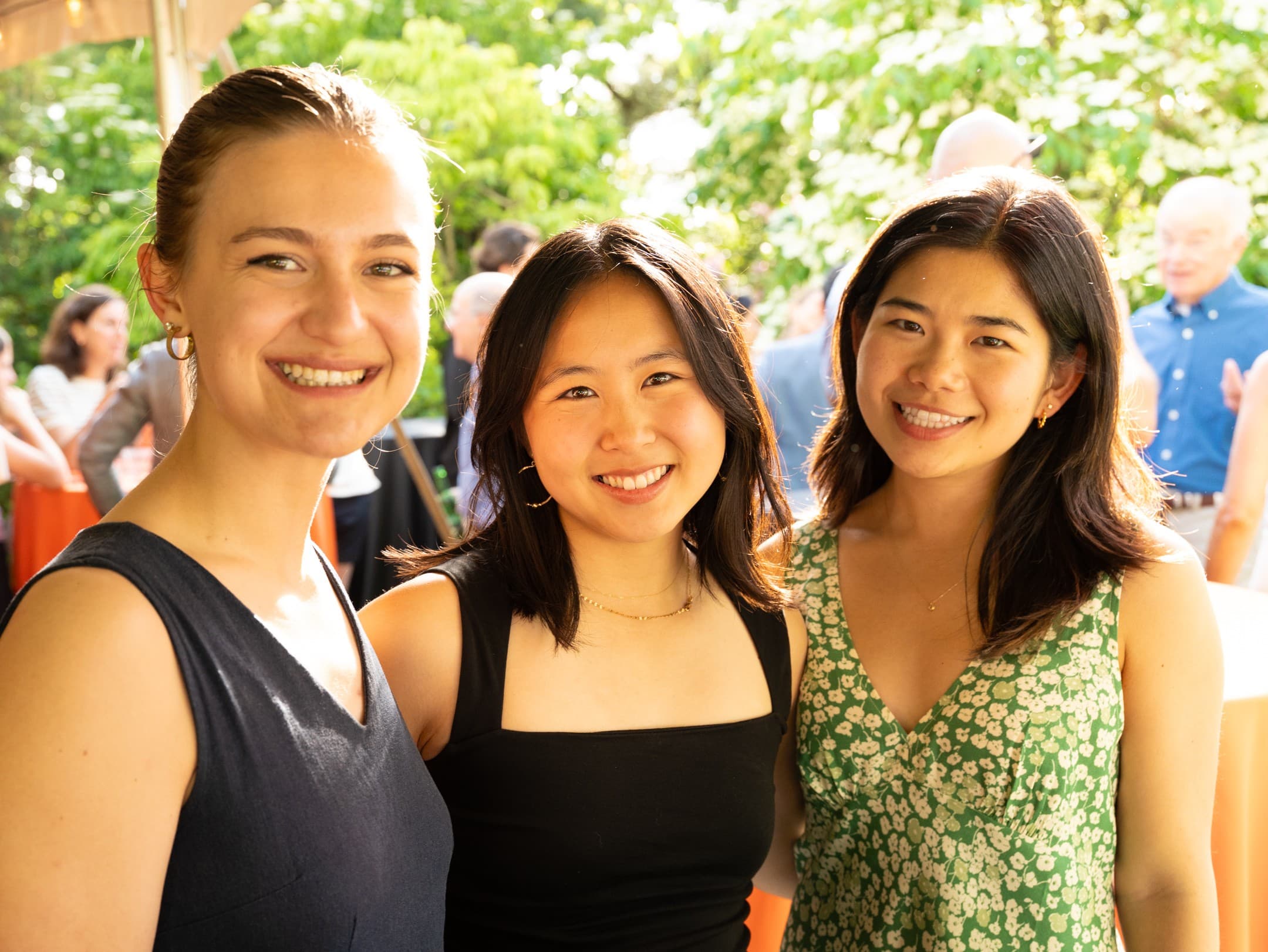 Three friends smiling outdoors at a private party